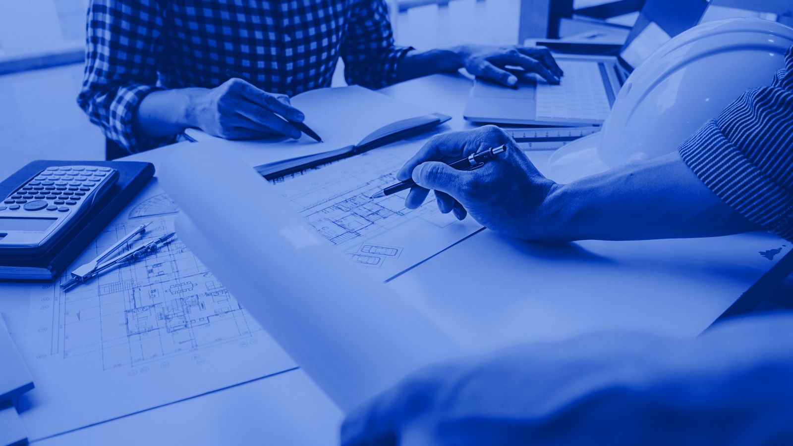 Ingenieros revisando planos estructurales sobre una mesa de trabajo